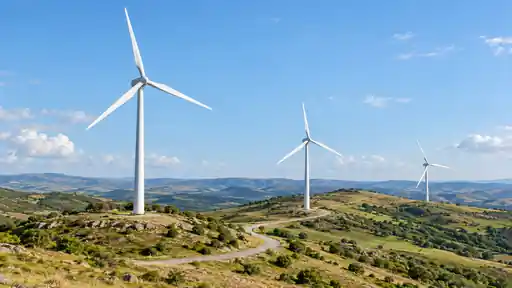 Açık tepelerde sıralanan markasız rüzgâr türbinleri ve kıvrılan servis yolu.